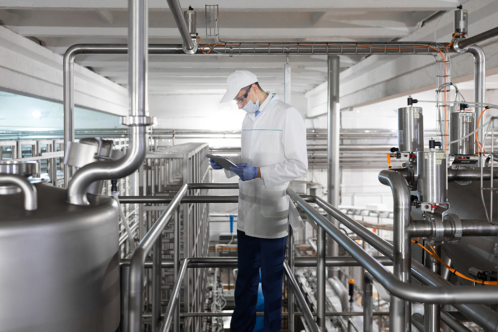Technologist stands with a tablet in the shop at the dairy Plant